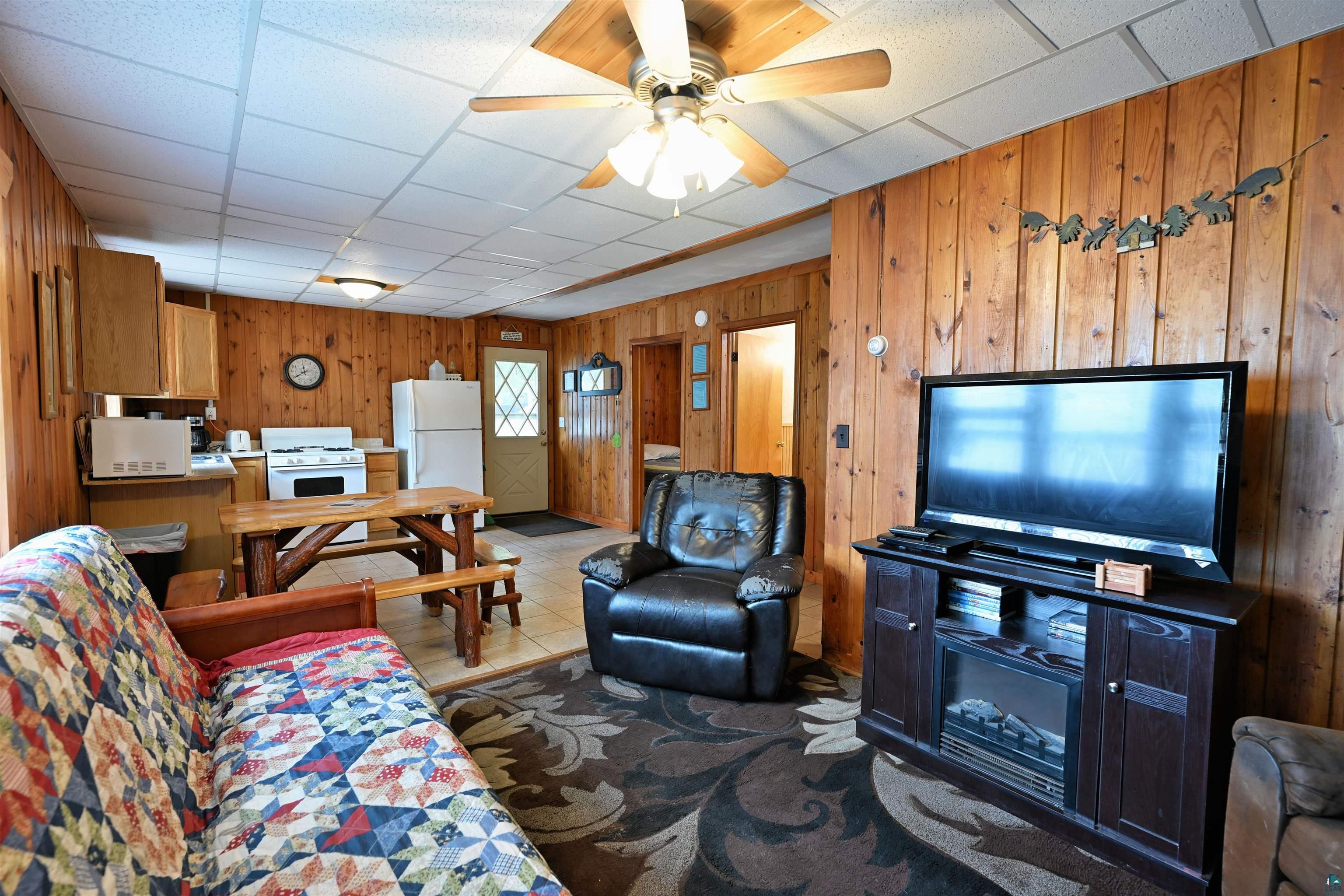 6833 View Point Lodge Road, Unit 14 Gordon, WI 54838 - Photo 22 of 34 Living room featuring wooden walls, a drop ceiling, ceiling fan, and dark tile patterned floors