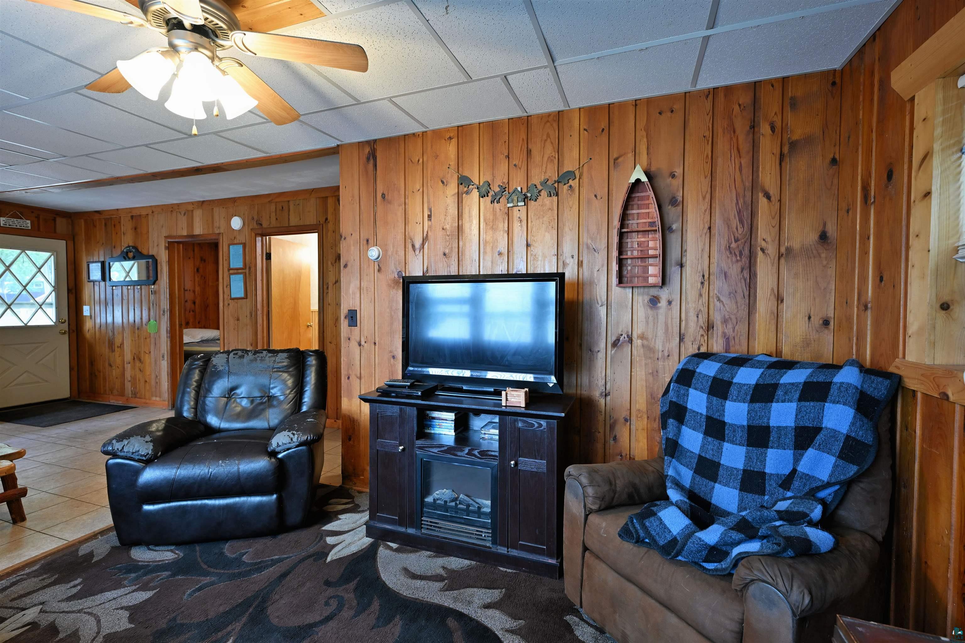 6833 View Point Lodge Road, Unit 14 Gordon, WI 54838 - Photo 23 of 34 Tiled living room featuring wood walls, a ceiling fan, and a paneled ceiling