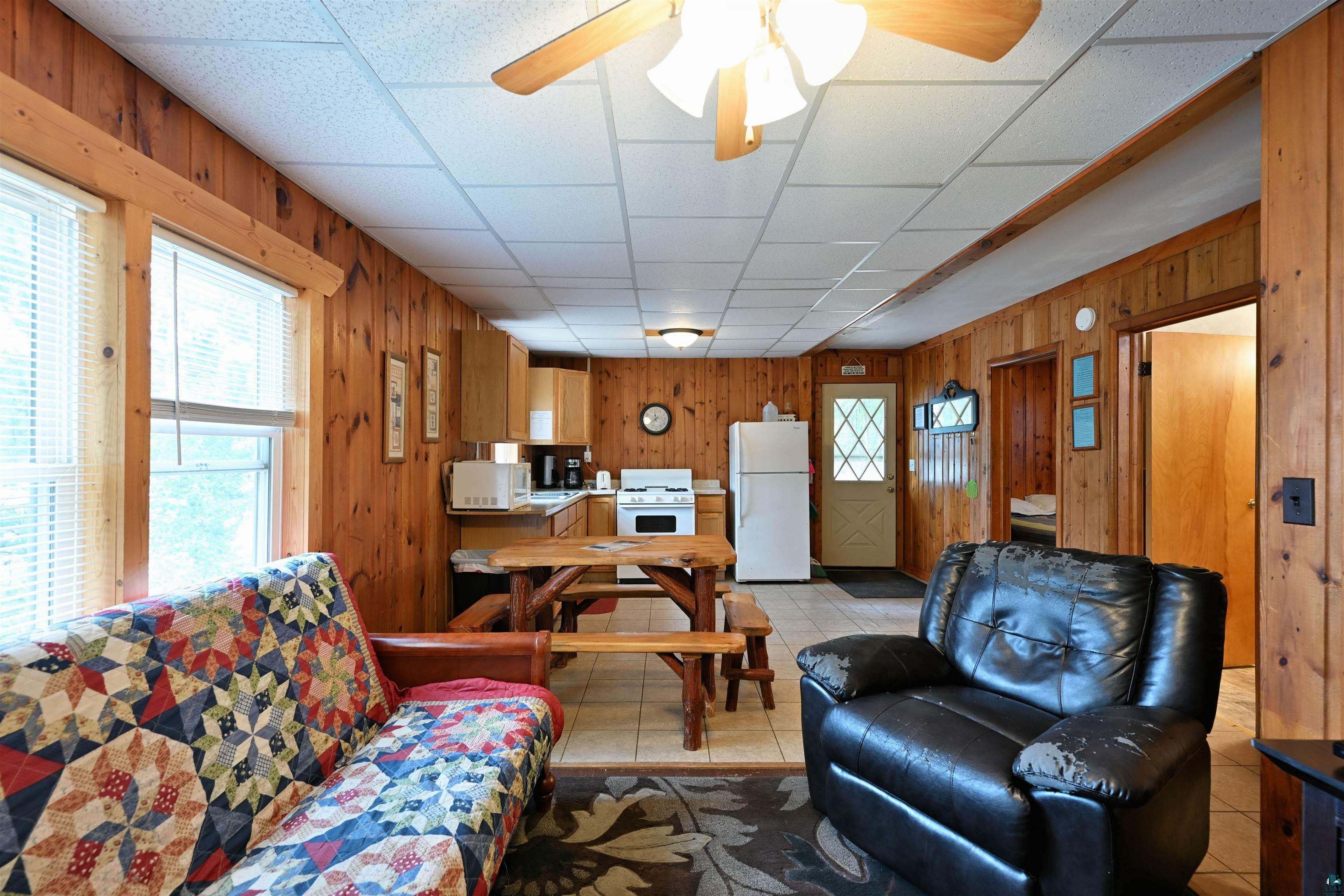 6833 View Point Lodge Road, Unit 14 Gordon, WI 54838 - Photo 24 of 34 Living area featuring a ceiling fan, a paneled ceiling, and wooden walls