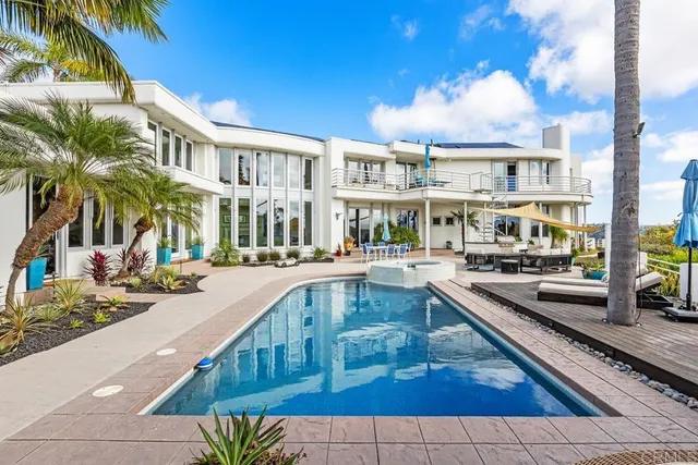a view of a swimming pool with a lounge chair and palm trees
