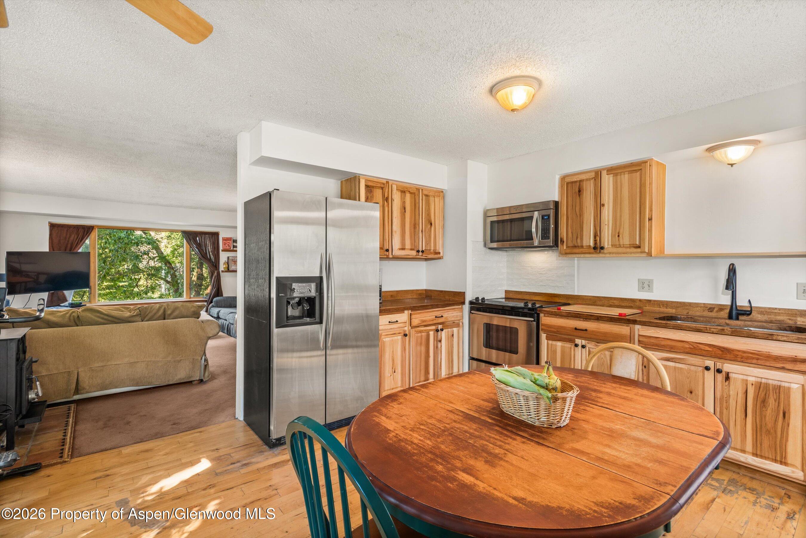 198 Holland Hills Road Basalt, CO 81621 - Photo 22 of 50 a kitchen with stainless steel appliances granite countertop a stove a refrigerator a sink a dining table and chairs with wooden floor