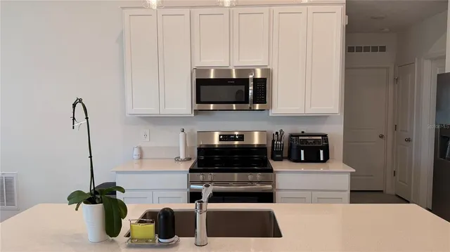 a kitchen with a stove and a white wooden cabinets