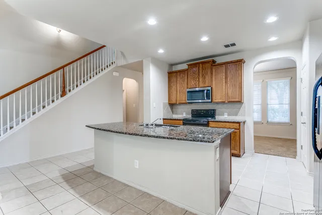 a kitchen with stainless steel appliances granite countertop a stove a sink and a refrigerator