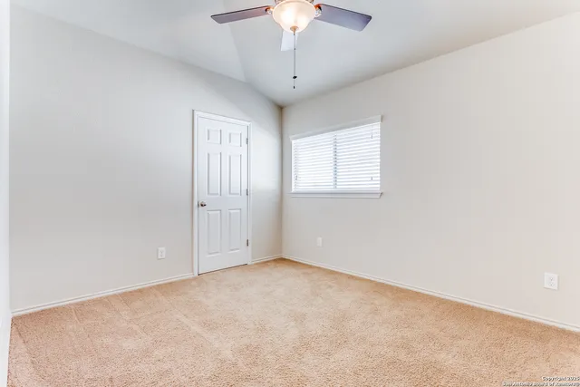 an empty room with a chandelier fan and windows