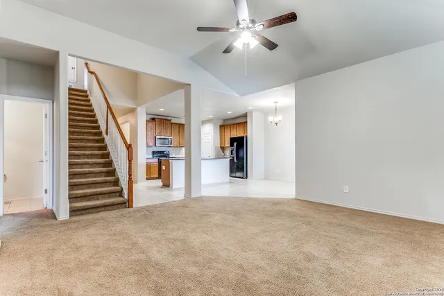 a view of an empty room with wooden floor and stairs