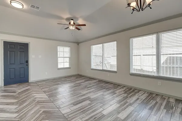 a view of an empty room with a window and wooden floor