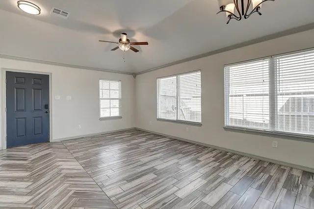 a view of an empty room with a window and wooden floor