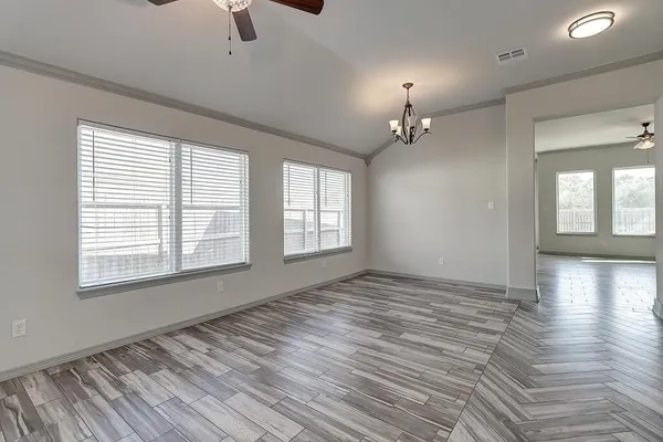 a view of an empty room with window and wooden floor
