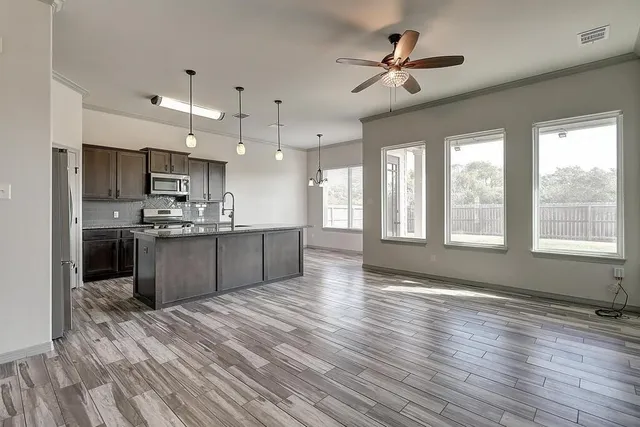 a large kitchen with stainless steel appliances kitchen island granite countertop a stove a refrigerator a sink a dining table and chairs with wooden floor
