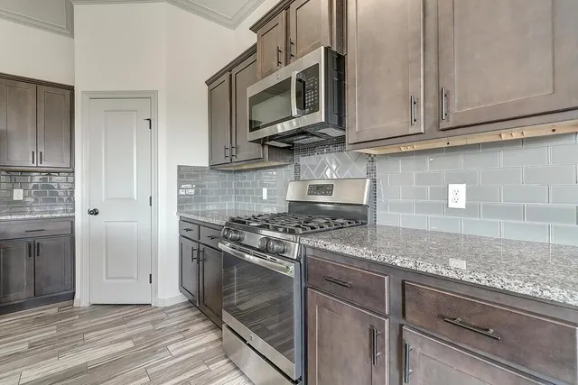 a kitchen with stainless steel appliances granite countertop a stove a microwave and a sink