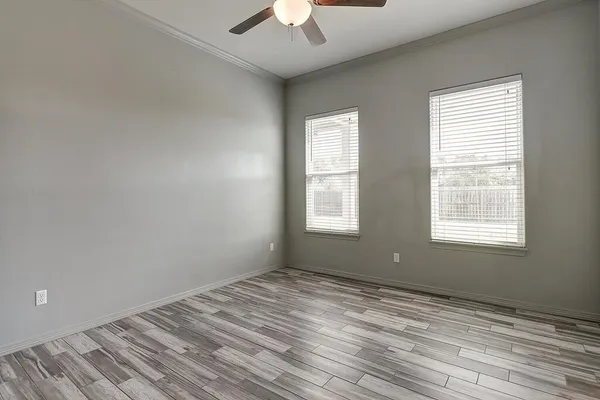 a view of empty room with wooden floor and fan