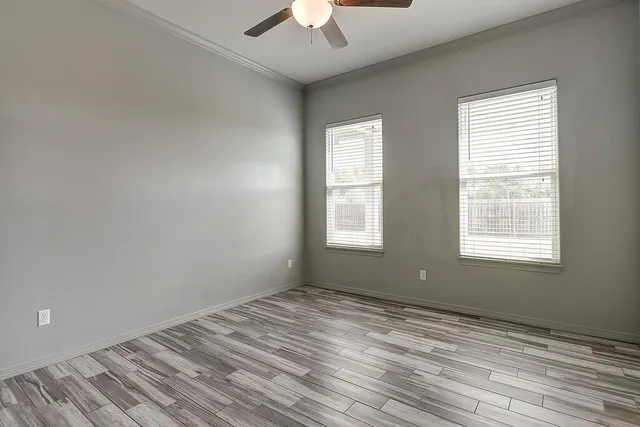 a view of empty room with wooden floor and fan