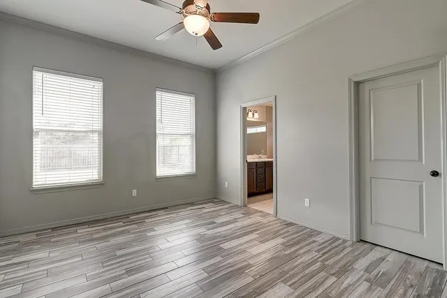 a view of an empty room with a window and wooden floor