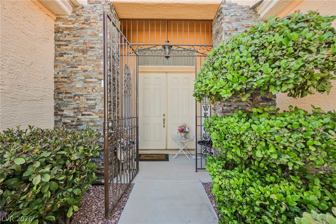 5494 Pine Ranch Street Las Vegas, NV 89113 - Photo 7 of 54 Secure entry via a decorative wrought iron gate leads to a classic double-door entryway framed by natural stone accents.
