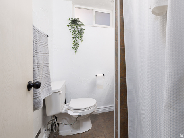 8252 Wood Street Midvale, UT 84047 - Photo 19 of 40 3/4 bathroom featuring a white toilet, frosted window, and light-colored walls