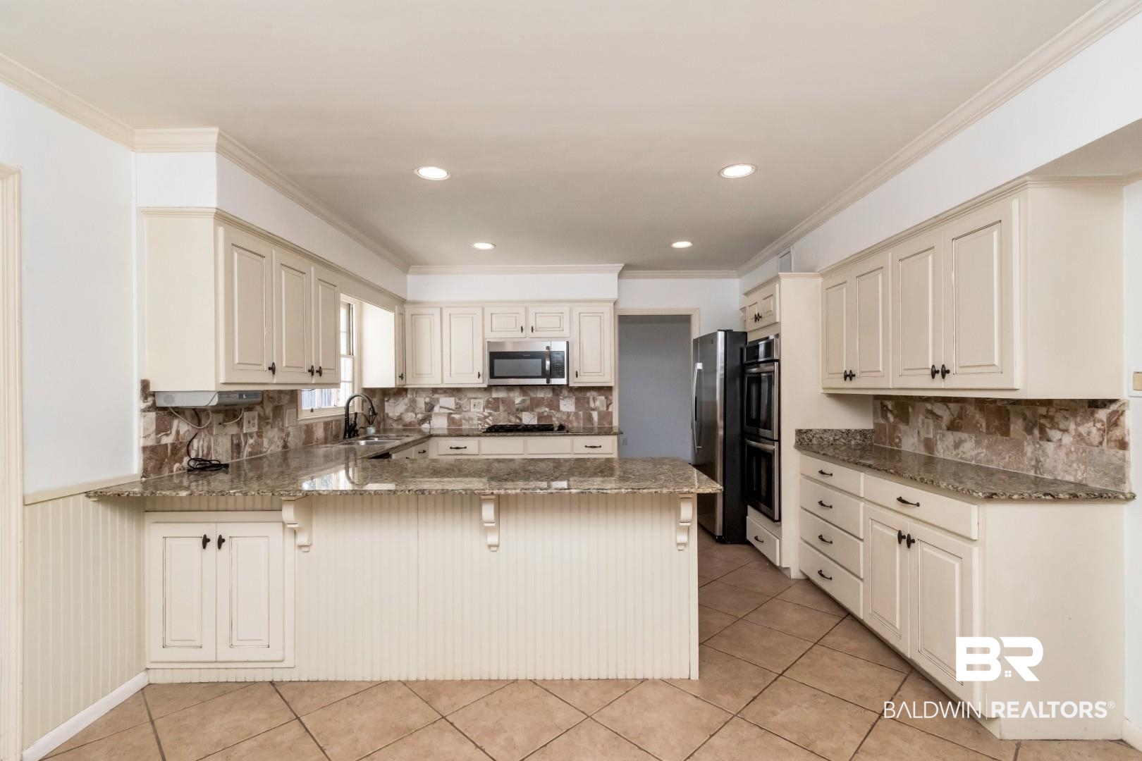 3755 Claridge Road North Mobile, AL 36608 - Photo 10 of 38 Kitchen with appliances with stainless steel finishes, a peninsula, a sink, a breakfast bar, and stone countertops