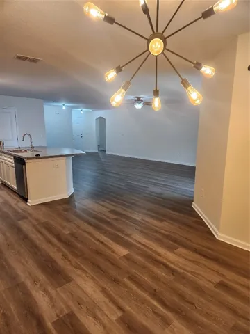 a view of kitchen and empty room with wooden floor