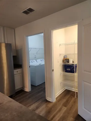 a view of a refrigerator in kitchen and an empty room with wooden floor windows
