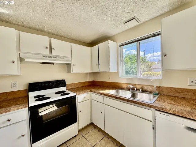 a kitchen with granite countertop white cabinets appliances and a sink