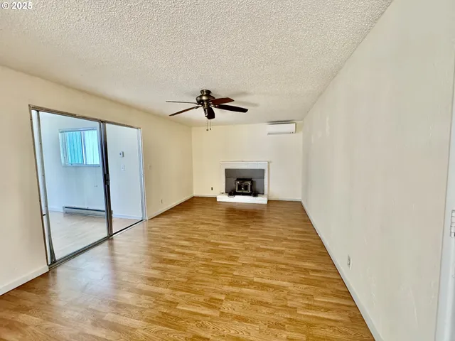 a view of empty room with wooden floor and fireplace