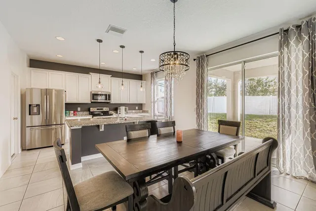 a kitchen with stainless steel appliances granite countertop a stove a refrigerator a kitchen island a table and chairs