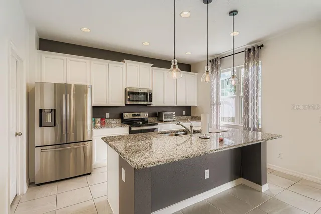 a kitchen with stainless steel appliances granite countertop a refrigerator a sink a stove a microwave and island