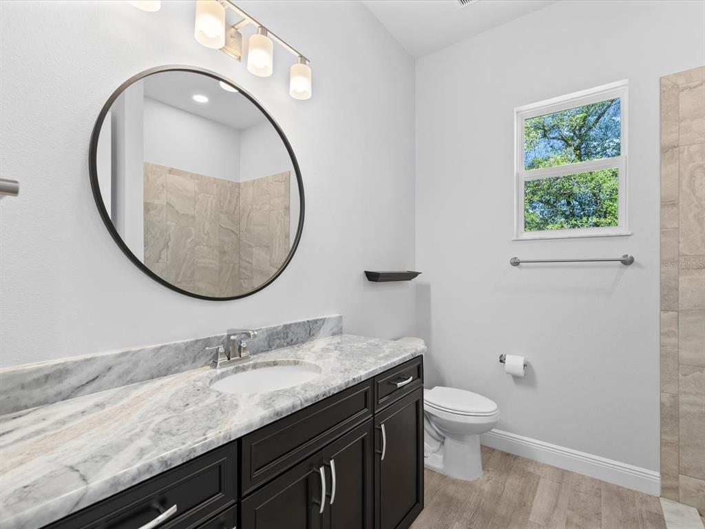 11981 Robina Road Weeki Wachee, FL 34614 - Photo 43 of 93 a bathroom with a granite countertop toilet a sink and a mirror