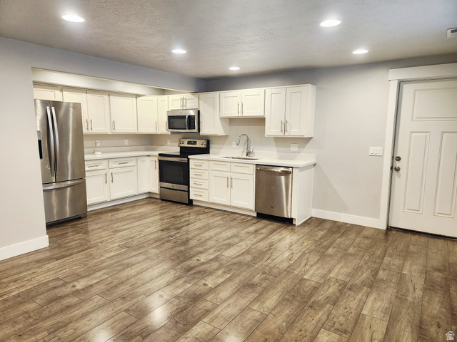 36 West Syracuse Road Vineyard, UT 84059 - Photo 49 of 56 Kitchen with wood-finish flooring, white cabinetry, light countertops, and recessed lighting