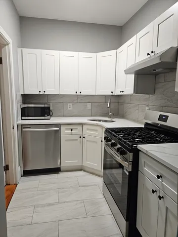 a kitchen with white cabinets and appliances