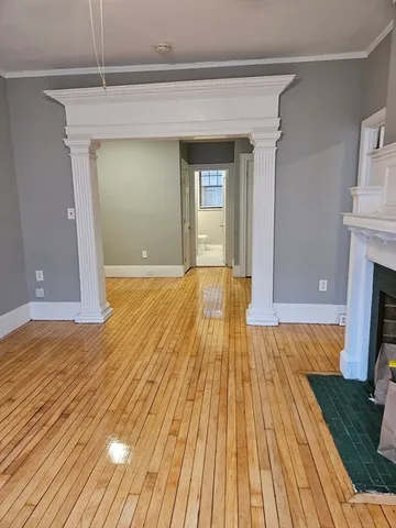a view of empty room with wooden floor and fireplace