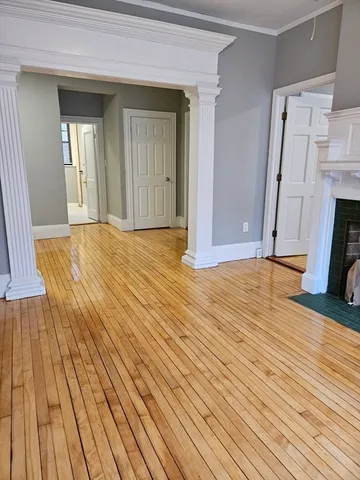 a view of empty room with wooden floor and fireplace