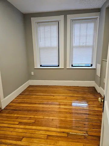 a view of kitchen and empty room with wooden floor