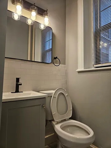 a bathroom with a toilet sink vanity and mirror