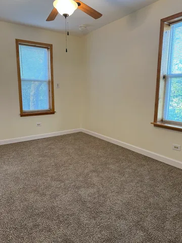 an empty room with a ceiling fan and window