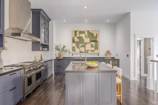 a kitchen with stainless steel appliances granite countertop a sink a stove and a wooden floors