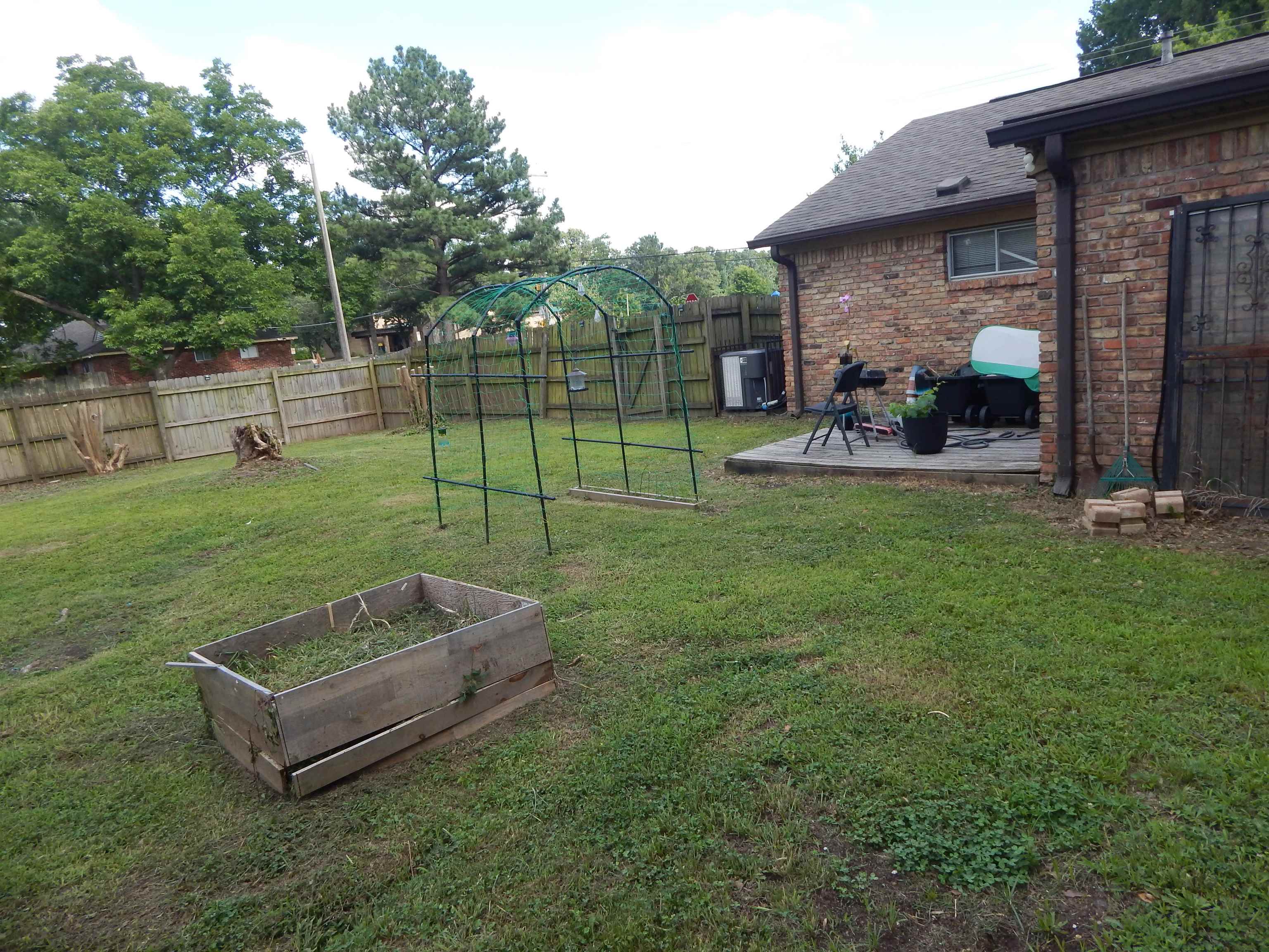 4956 Cottonwood Road Memphis, TN 38118 - Photo 2 of 13 Expansive backyard featuring a wood privacy fence, a raised garden bed, and a brick exterior with a patio area