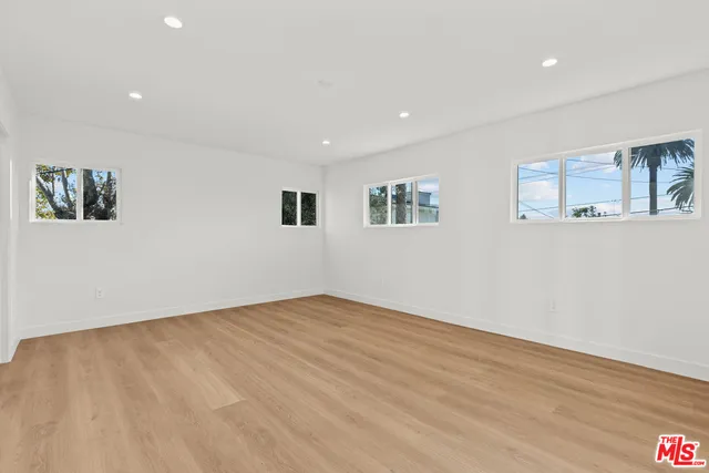 a view of an empty room with wooden floor and window