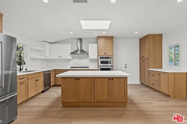 a large kitchen with stainless steel appliances granite countertop a stove a sink dishwasher and a refrigerator