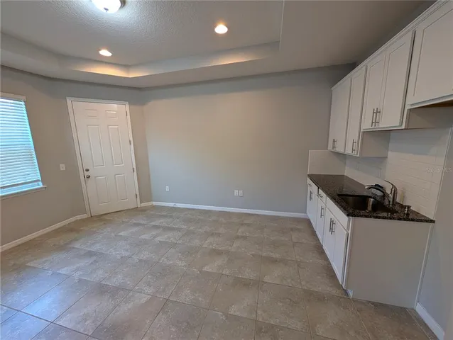a view of a kitchen with a sink and dishwasher a refrigerator with white cabinets