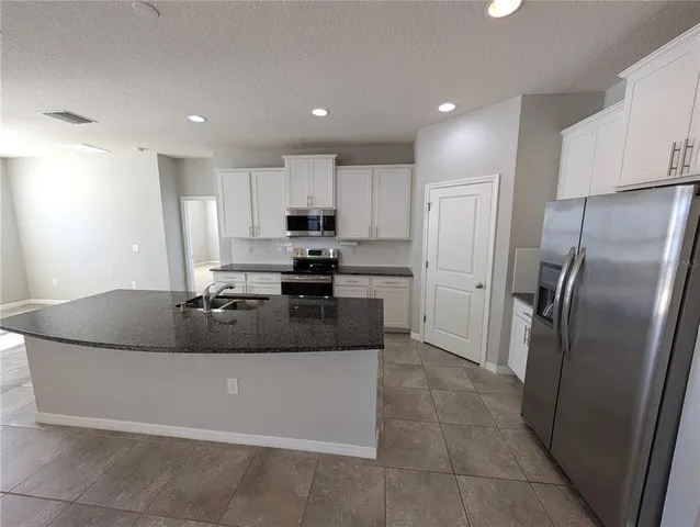 a kitchen with stainless steel appliances granite countertop a refrigerator a stove a sink and a refrigerator