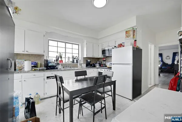 a kitchen with refrigerator a stove a sink and chairs