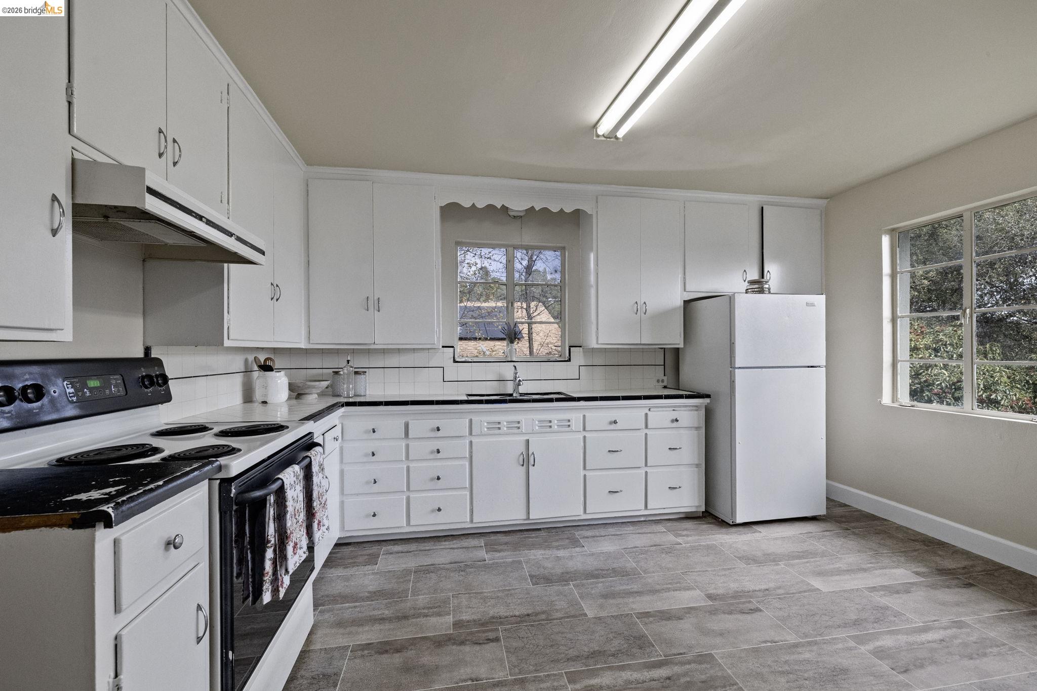 299 Summit Avenue Sonora, CA 95370 - Photo 11 of 38 Kitchen with electric range, white cabinetry, freestanding refrigerator, and under cabinet range hood