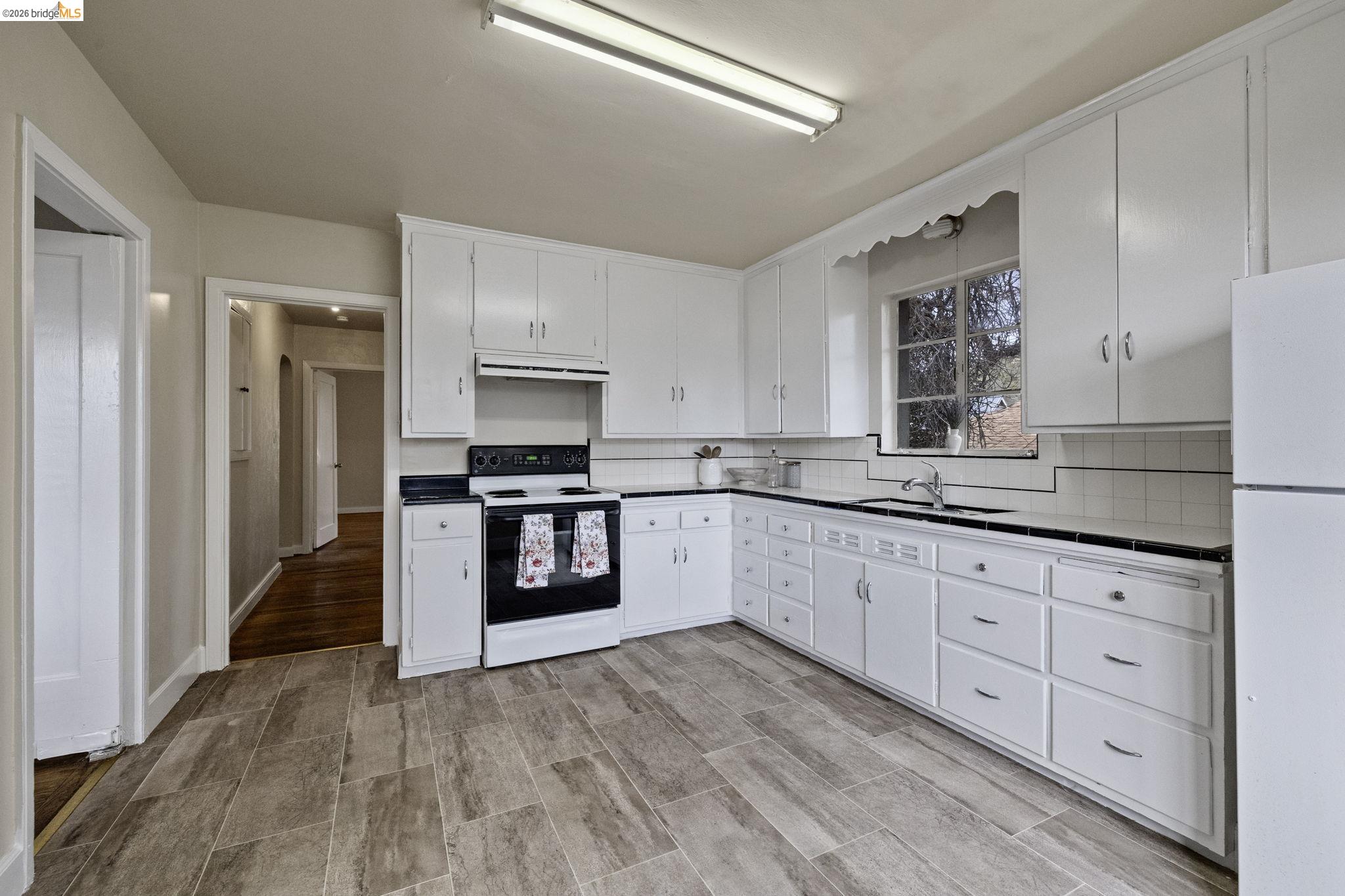 299 Summit Avenue Sonora, CA 95370 - Photo 12 of 38 Kitchen featuring electric range oven, freestanding refrigerator, white cabinetry, and backsplash