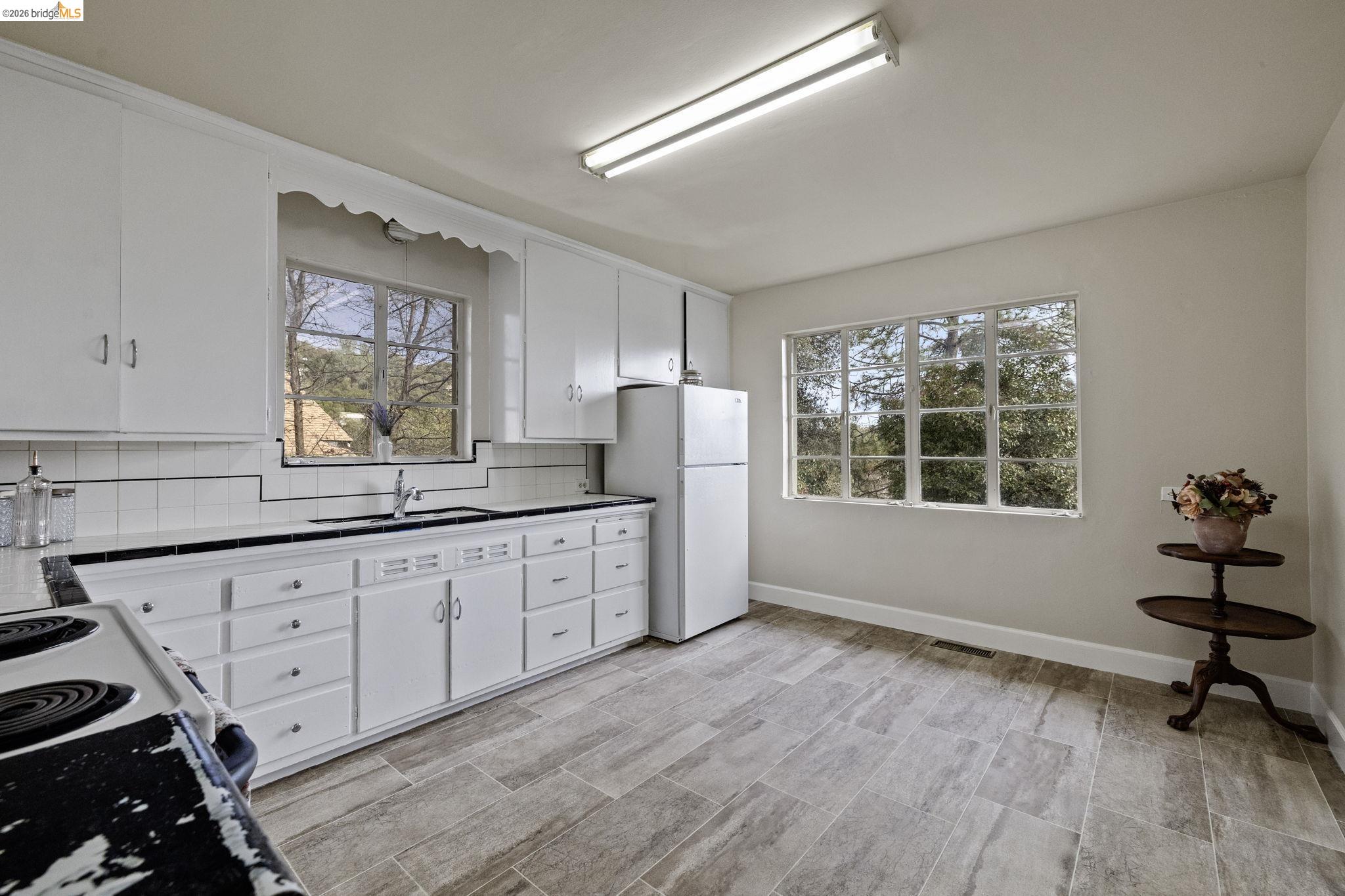 299 Summit Avenue Sonora, CA 95370 - Photo 10 of 38 Kitchen featuring white cabinetry, backsplash, freestanding refrigerator, and plenty of natural light