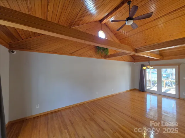 a view of an empty room with window and wooden floor