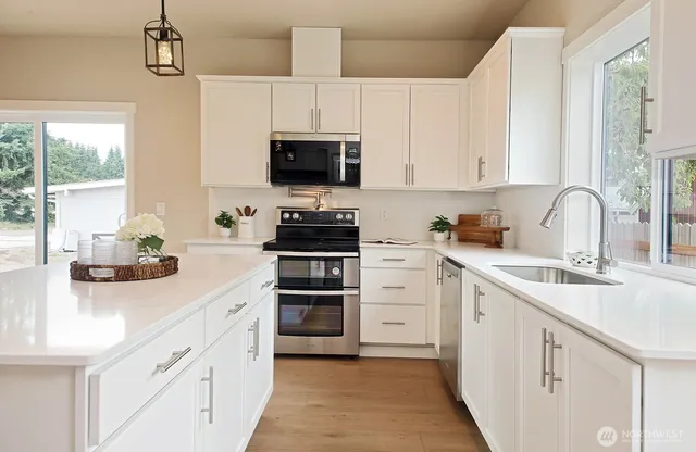 a kitchen with stainless steel appliances a sink a stove and cabinets
