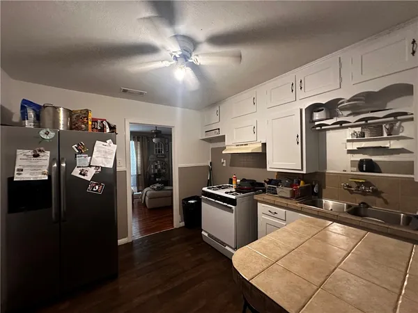 a kitchen with stainless steel appliances kitchen island granite countertop a refrigerator a sink a stove and oven with wooden floor