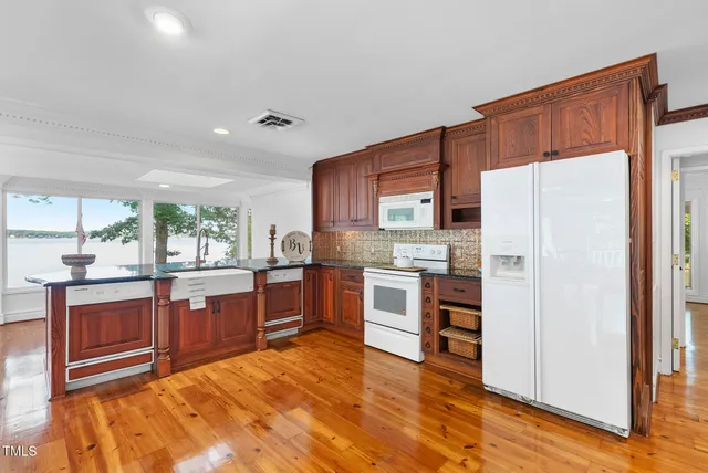 a kitchen with stainless steel appliances granite countertop a refrigerator a sink dishwasher a stove with wooden cabinets and floor