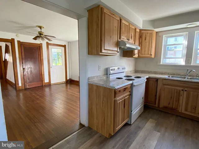 a kitchen with stainless steel appliances granite countertop a sink a stove a refrigerator cabinets and wooden floor