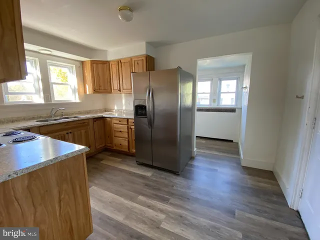 a kitchen with stainless steel appliances granite countertop a refrigerator a sink a stove and wooden floors